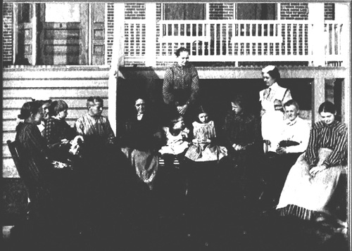 Female residents sit outside the dormitory